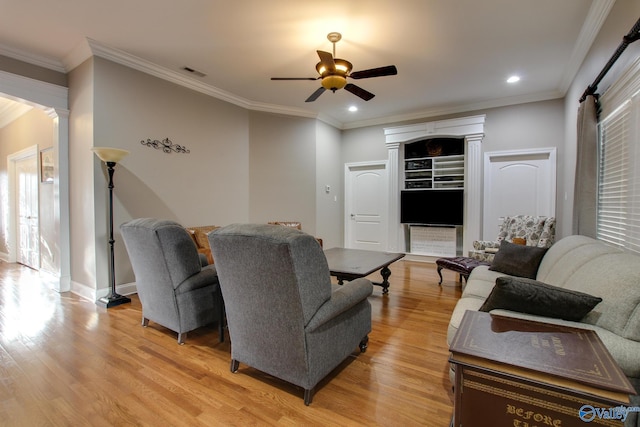 living room featuring visible vents, ceiling fan, crown molding, and light wood-style flooring