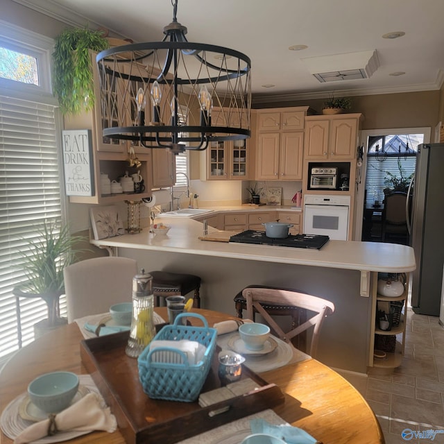 kitchen featuring kitchen peninsula, appliances with stainless steel finishes, ornamental molding, sink, and an inviting chandelier