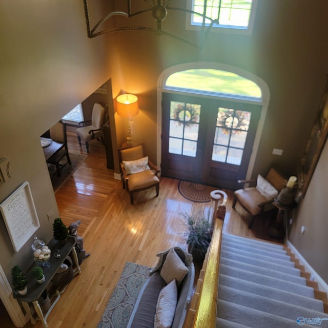 living room with french doors, hardwood / wood-style floors, a towering ceiling, and plenty of natural light