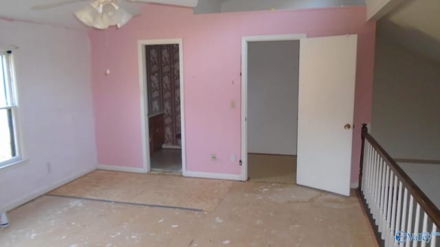 unfurnished bedroom with multiple windows, baseboards, and a walk in closet