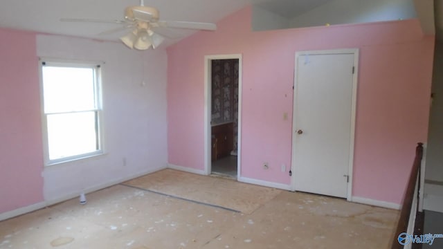 unfurnished bedroom with lofted ceiling, connected bathroom, and baseboards