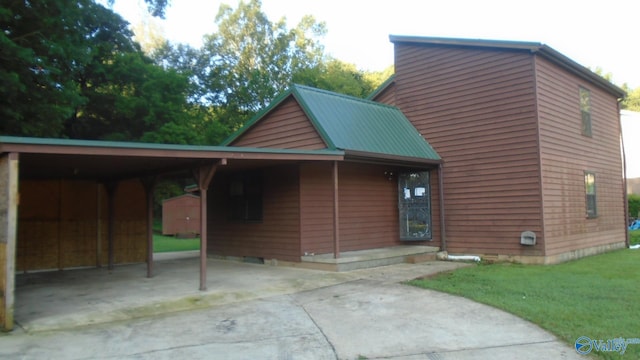 view of front of house featuring driveway, metal roof, an attached carport, and a front yard
