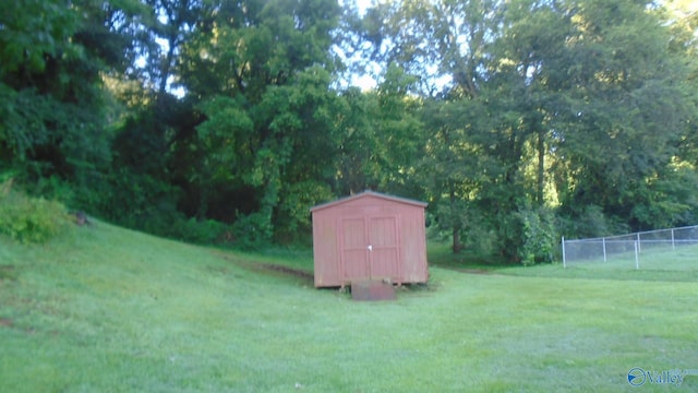 view of yard with a shed, fence, and an outbuilding