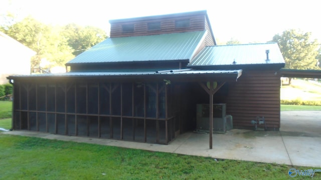 back of house with metal roof, a patio, and a sunroom