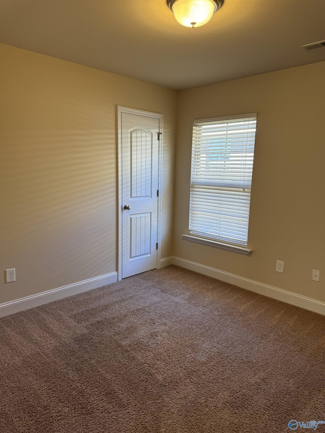 empty room featuring visible vents, carpet, and baseboards