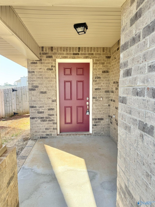 property entrance featuring brick siding and fence