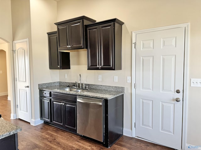 kitchen with a sink, arched walkways, stainless steel dishwasher, and dark wood-style floors