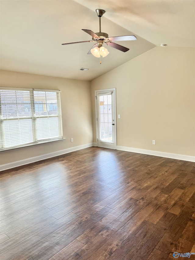 empty room with visible vents, baseboards, ceiling fan, vaulted ceiling, and dark wood-style flooring