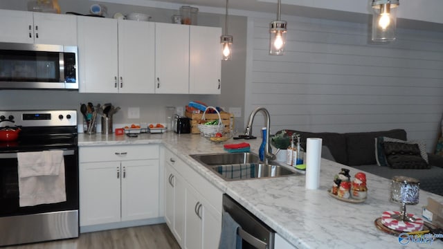 kitchen featuring light wood finished floors, white cabinetry, stainless steel appliances, and a sink