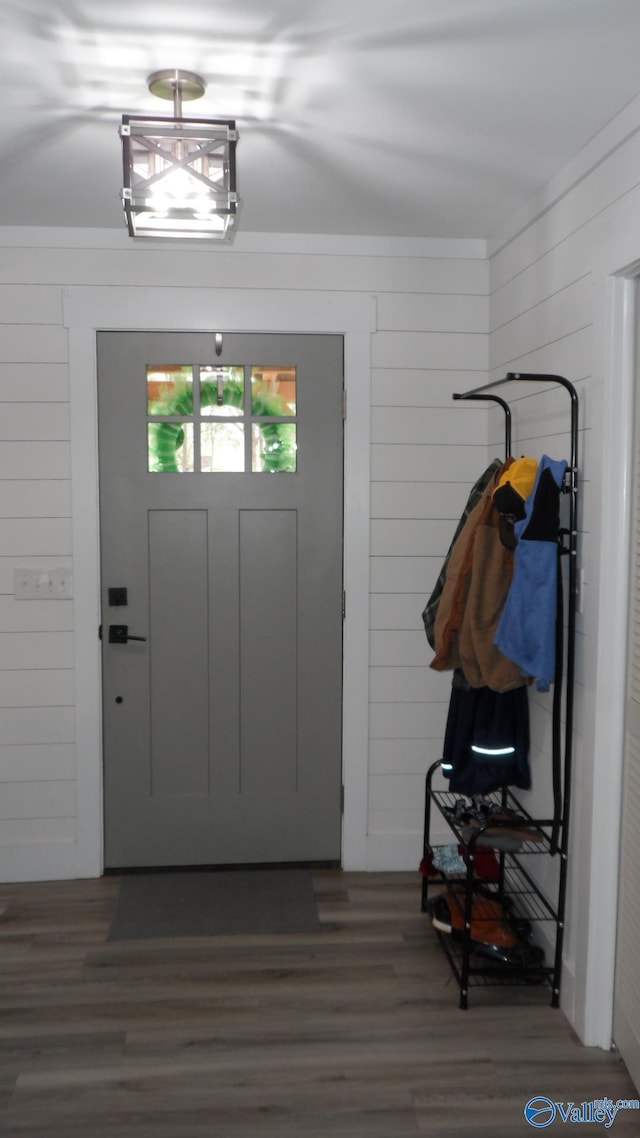 foyer entrance featuring wood finished floors, ornamental molding, and wood walls