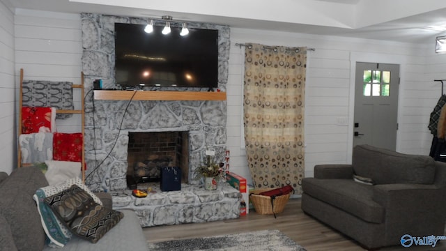 living area with wood finished floors, a fireplace, and wood walls