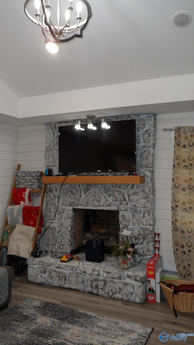 living area featuring a chandelier, a fireplace, and wood finished floors