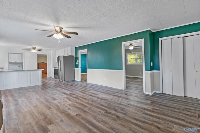 unfurnished living room with ornamental molding, ceiling fan, and dark hardwood / wood-style floors