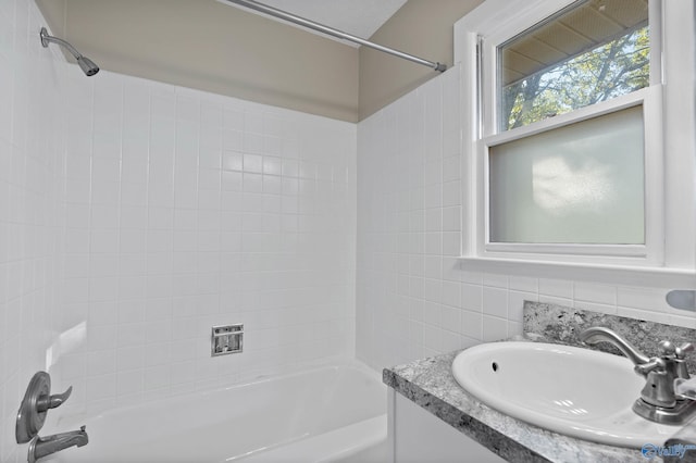 bathroom featuring tile walls, tiled shower / bath combo, and vanity