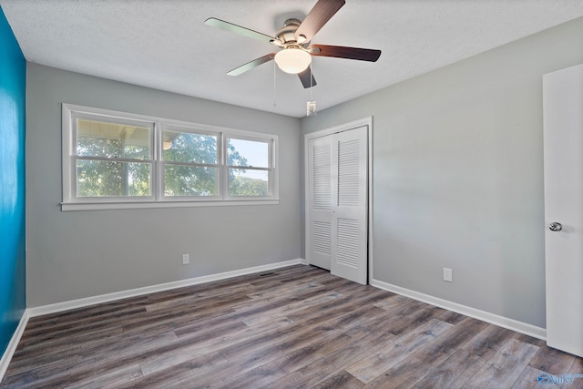 unfurnished bedroom with a closet, ceiling fan, a textured ceiling, and dark hardwood / wood-style flooring