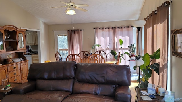 living room featuring lofted ceiling, a textured ceiling, and a ceiling fan