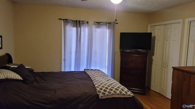 bedroom with a textured ceiling, ceiling fan, and wood finished floors