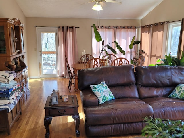 living room with a ceiling fan, vaulted ceiling, and wood finished floors