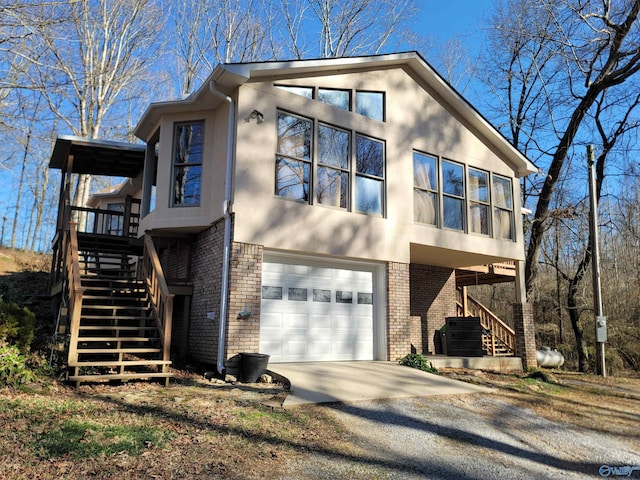 view of front of home featuring brick siding, stucco siding, concrete driveway, central AC, and stairs