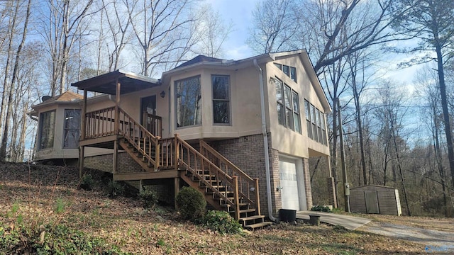 view of home's exterior with brick siding, stucco siding, stairway, a storage shed, and driveway