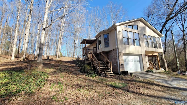 view of side of property featuring a garage, brick siding, concrete driveway, stairway, and stucco siding