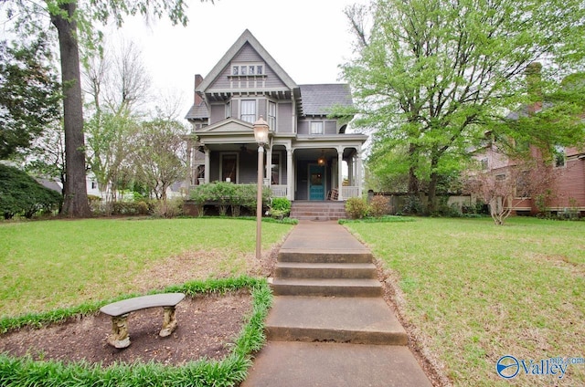 victorian house featuring covered porch, a chimney, and a front lawn