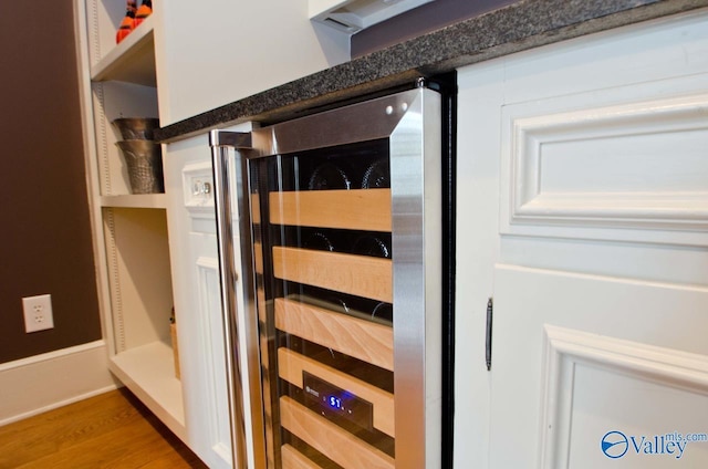 details with dark countertops, beverage cooler, and wood finished floors