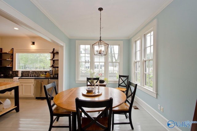 dining area with a wealth of natural light, baseboards, a chandelier, and crown molding