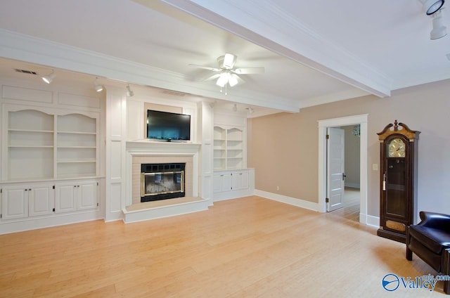 unfurnished living room with baseboards, light wood-style floors, ornamental molding, beam ceiling, and a glass covered fireplace