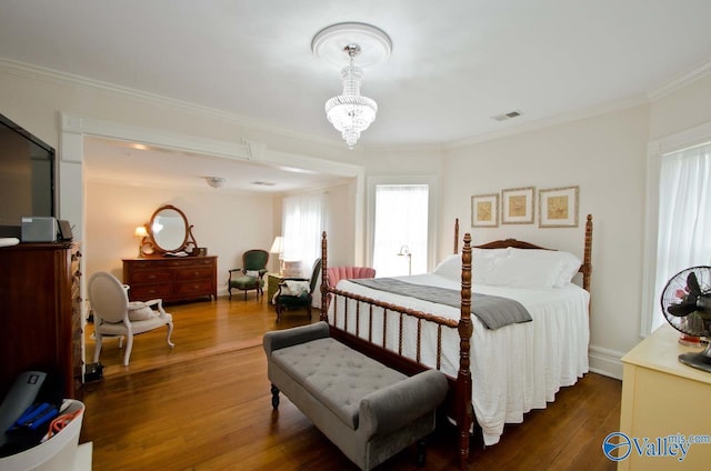 bedroom featuring visible vents, crown molding, a notable chandelier, and wood finished floors