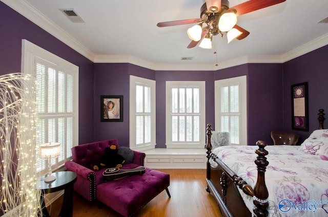 bedroom with a ceiling fan, crown molding, visible vents, and wood finished floors