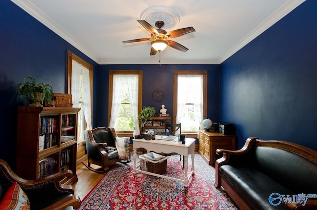 sitting room with ceiling fan, crown molding, and wood finished floors