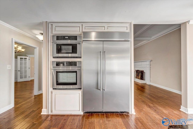 kitchen with crown molding, stainless steel appliances, and light hardwood / wood-style floors