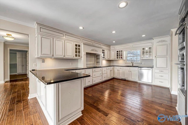 kitchen featuring appliances with stainless steel finishes, white cabinets, kitchen peninsula, crown molding, and dark wood-type flooring