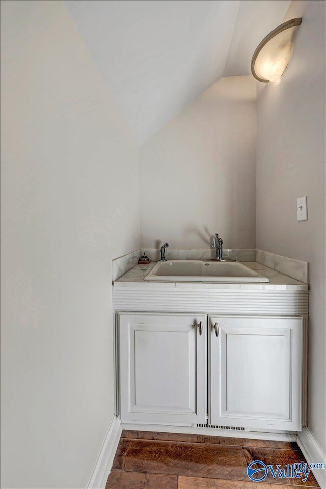 bathroom with hardwood / wood-style flooring, lofted ceiling, and sink