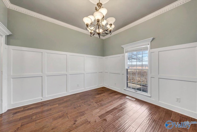 empty room featuring ornamental molding, dark hardwood / wood-style floors, and a chandelier