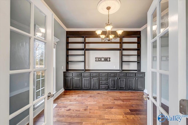 interior space featuring an inviting chandelier, crown molding, light hardwood / wood-style flooring, and french doors