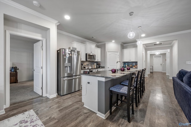 137 Sunlit Grove Dr, Harvest, AL 35749 - kitchen featuring stainless steel appliances, dark wood-type flooring, white cabinetry, a kitchen breakfast bar, and a center island with sink