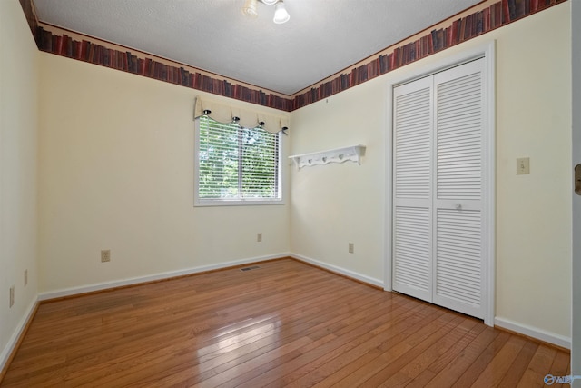 unfurnished bedroom featuring hardwood / wood-style flooring, a closet, and a textured ceiling