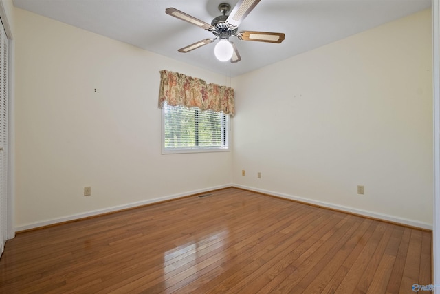 unfurnished room with a ceiling fan, visible vents, baseboards, and wood finished floors