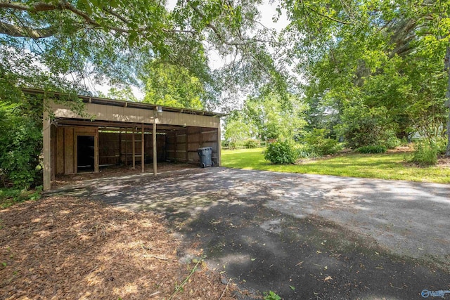 view of pole building with a yard, a carport, and aphalt driveway