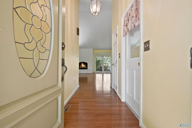 hall with wood finished floors, visible vents, and baseboards