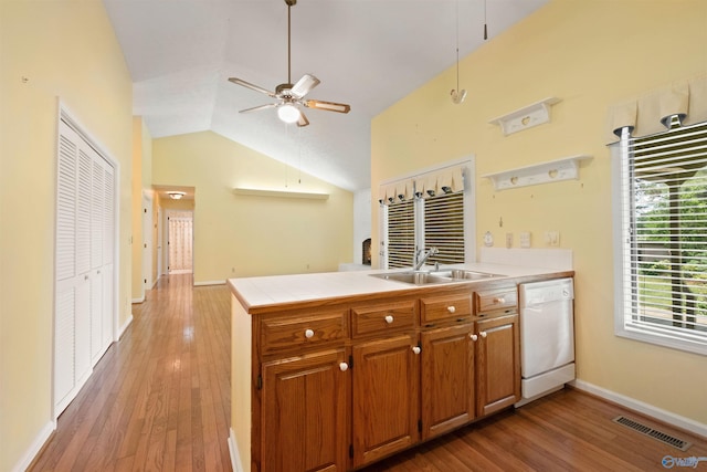 kitchen featuring a peninsula, a sink, visible vents, brown cabinets, and dishwasher