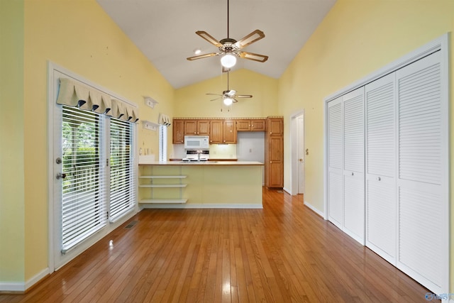 kitchen with high vaulted ceiling, light hardwood / wood-style flooring, kitchen peninsula, and ceiling fan