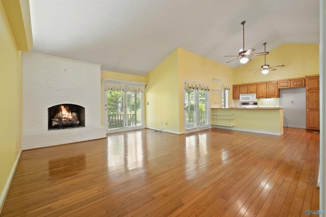 unfurnished living room featuring ceiling fan, high vaulted ceiling, a fireplace, baseboards, and light wood-style floors