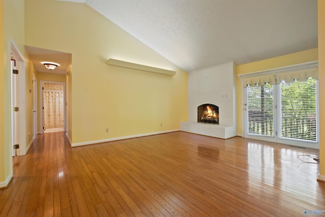 unfurnished living room with a fireplace, visible vents, high vaulted ceiling, light wood-type flooring, and baseboards