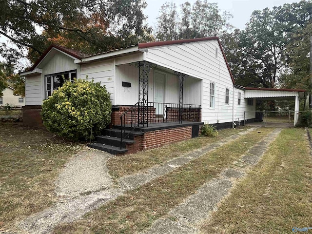 view of front facade with a front lawn, a carport, and a porch