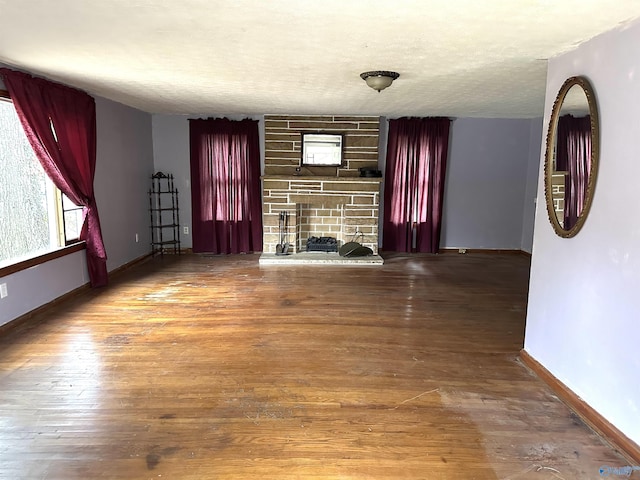 unfurnished living room with hardwood / wood-style flooring, a fireplace, and a textured ceiling