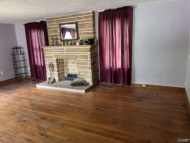 unfurnished living room featuring dark hardwood / wood-style flooring, a fireplace, and a textured ceiling