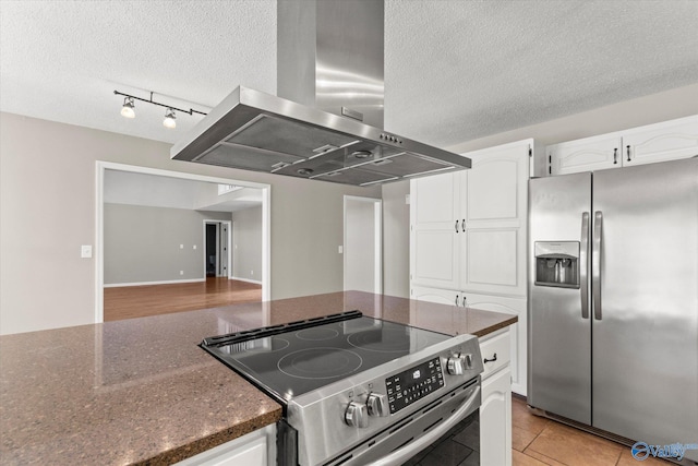 kitchen featuring a textured ceiling, white cabinets, stainless steel appliances, and extractor fan